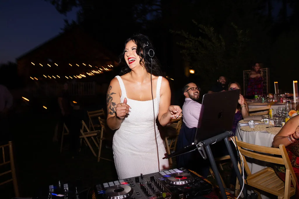 DJ Mami Miami, a Latina DJ, in Bridal Gown with big smile and behind DJ controller decks